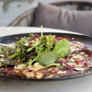 a plate of food on a table with a variety of colorful dishes, including vegetables, rice, and grilled chicken